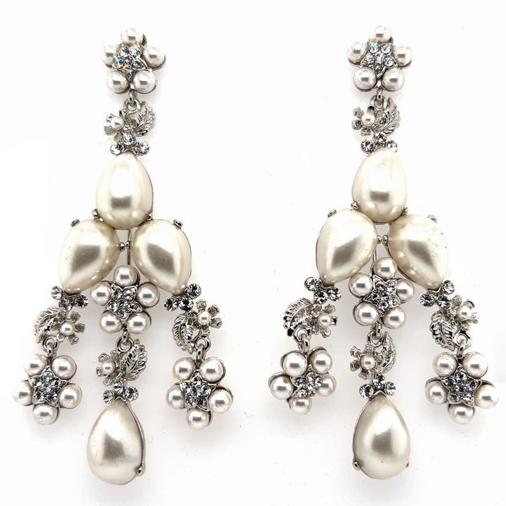 The Floral Pearl Statement Chandelier Earrings (style no. E215) feature ornate silver details, teardrop-shaped genuine pearls, and clusters of small round pearls—an intricate design ideal for bridal jewelry.