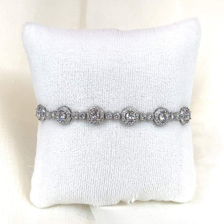 The Luxurious Bridal Bracelet (style no. HGB1986) in silver features sparkling circular CZ diamonds, elegantly displayed on a white textured cushion.