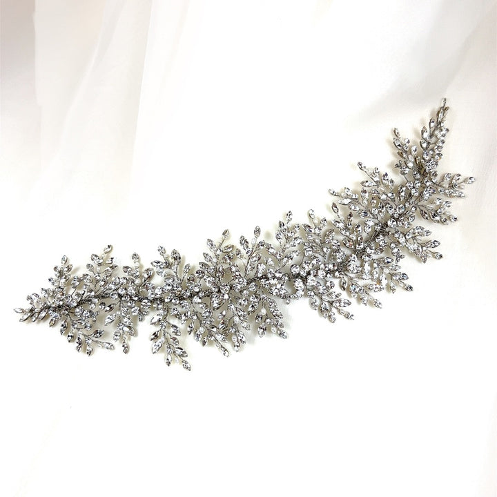 The Glistening Cluster Vine (style no. 3951567) is a stunning Swarovski crystal wedding accessory, intricately adorned with numerous small, leaf-shaped crystals in a flowing, elegant pattern.