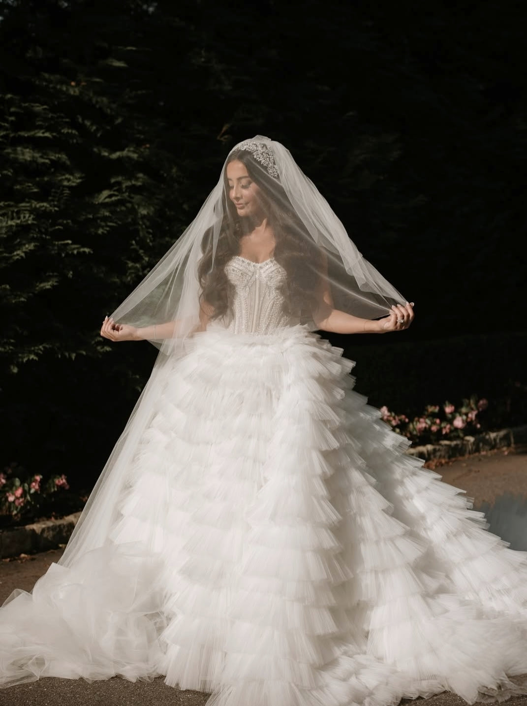 Nicolette wearing her custom Swarovski crystal bridal headpiece from Bridal Styles Boutique, cathedral veil, and tiered tulle ball gown in an outdoor night portrait.