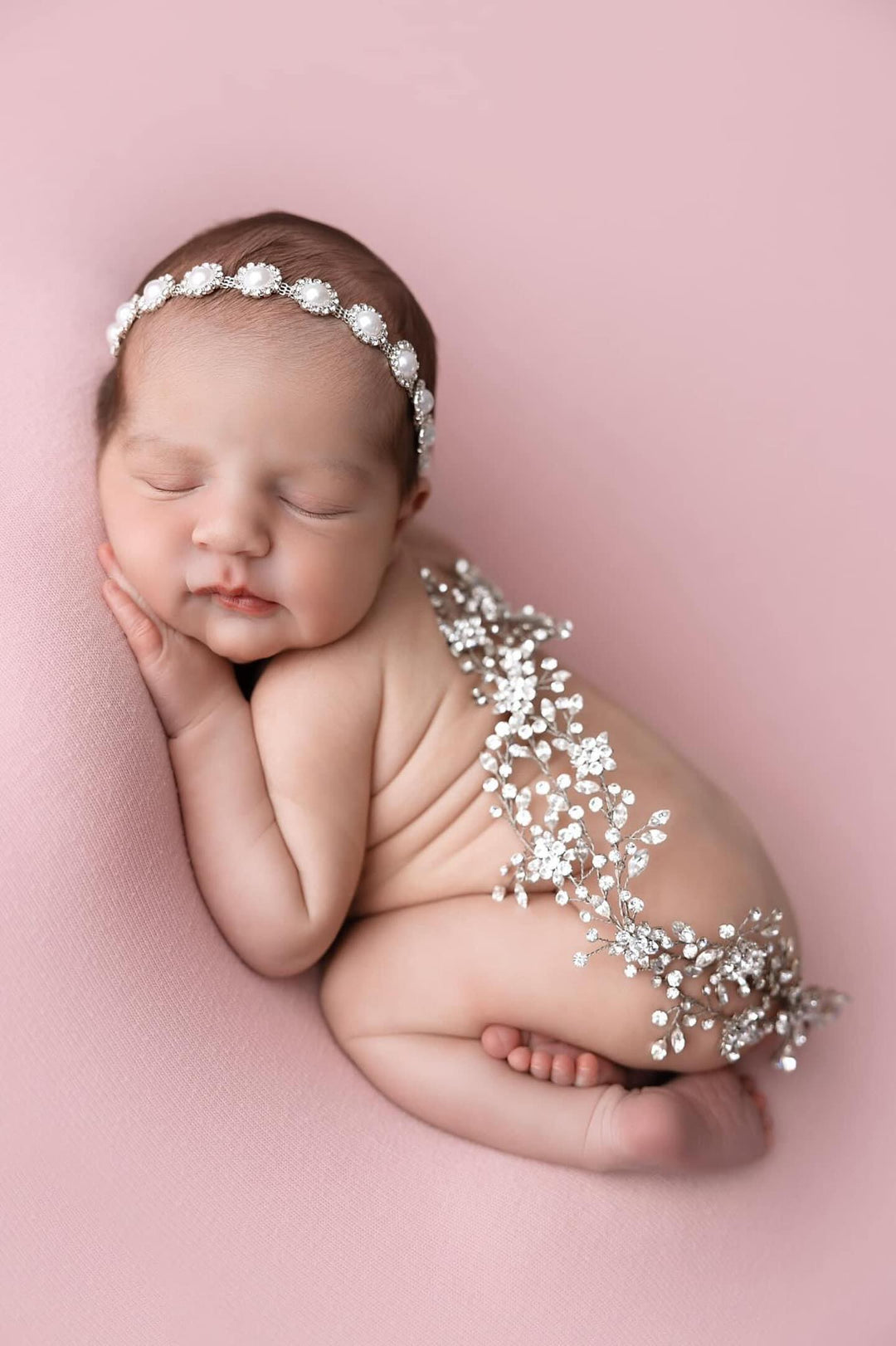 Newborn baby sleeping in a pearl and crystal bridal headband Bridal Styles Boutique wedding hair vine draped across her back 