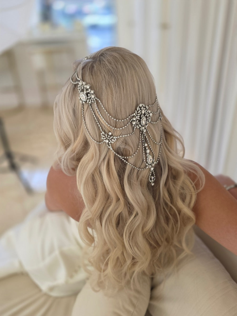 Bride wearing draped bridal head jewelry, layered crystal chains and medallions cascading over long blonde waves