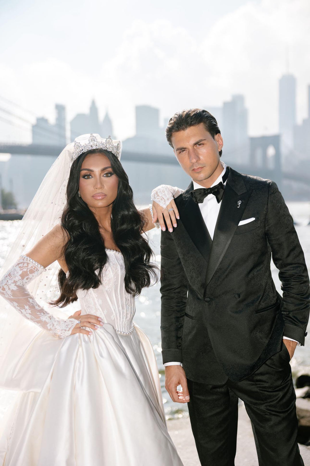 Bride Daniella wearing a wedding tiara crown and crystallized cathedral veil with her groom against the Brooklyn Bridge and New York City skyline