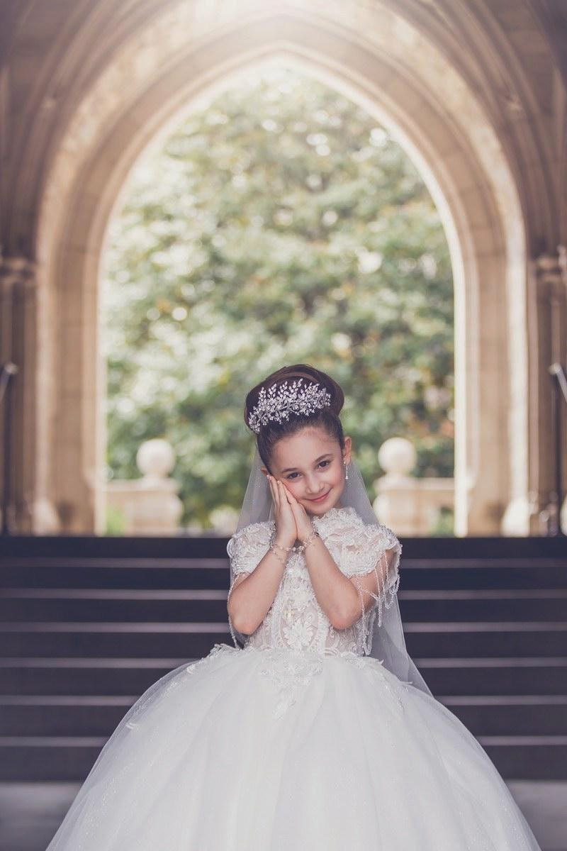 Girl in First Communion dress wearing crystal tiara communion headpiece and veil at church