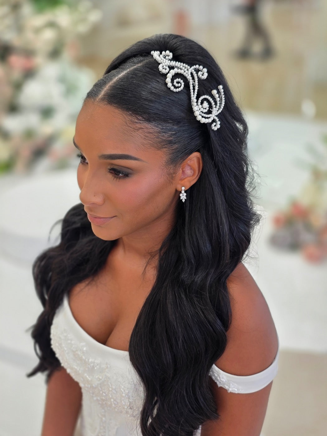 Bride wearing a pearl and crystal bridal hair comb positioned to the side in a half-up hairstyle with long soft waves