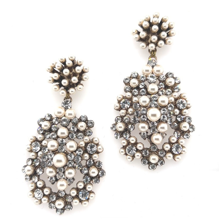 The Studded Pearl and Crystal Chandelier Earrings (style no. E218) dazzle with white pearls and clear crystals in floral patterns on a silver-tone base—ideal as statement bridal jewelry.