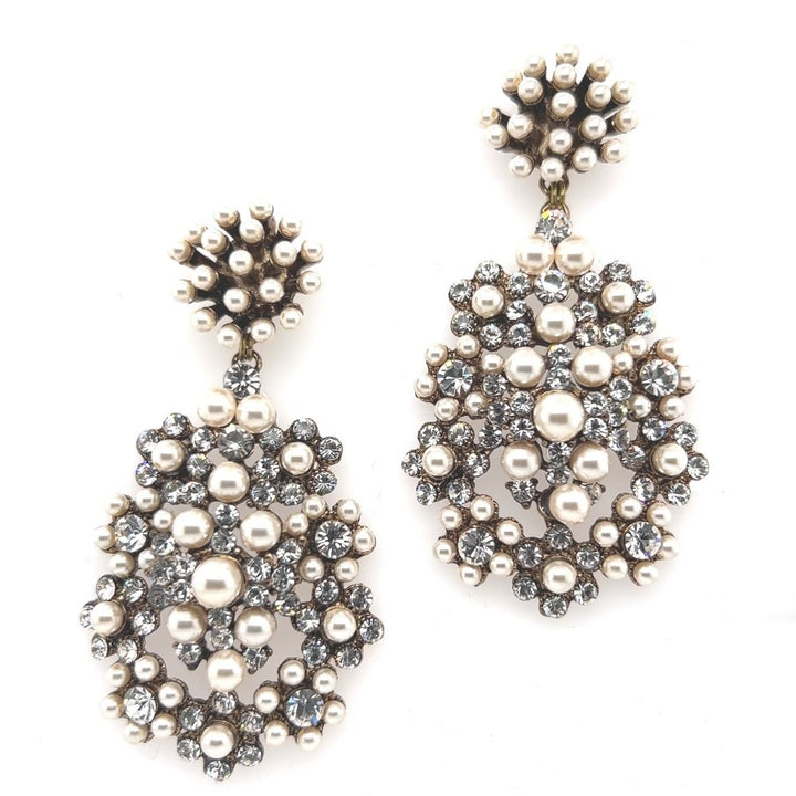 The Studded Pearl and Crystal Chandelier Earrings (style no. E218) dazzle with white pearls and clear crystals in floral patterns on a silver-tone base—ideal as statement bridal jewelry.