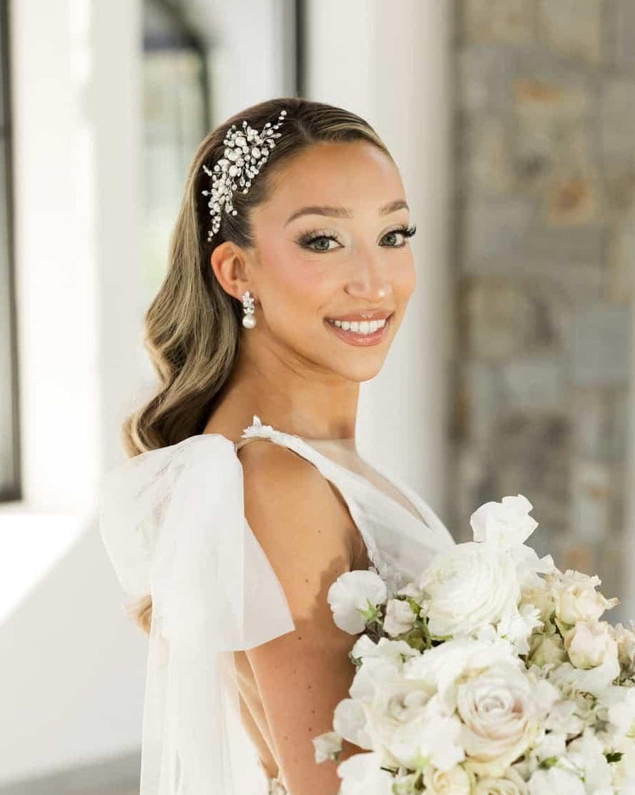 Bride holding a bouquet with decorative pearl and crystal comb headpiece and earrings.