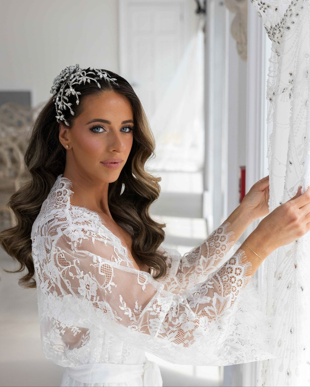 Brown hair bride with long flowing curls and beautiful blue eyes wearing a dramatic Swarovski crystal flower comb bridal headpiece on the side.