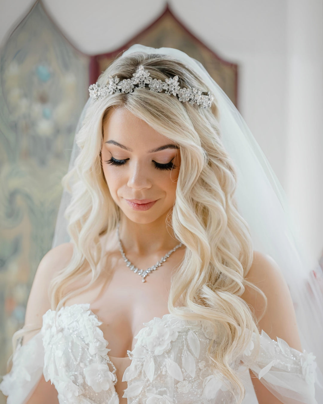 Blond bride looking down wearing a crystal bridal tiara and jewelry by Bridal Styles Boutique