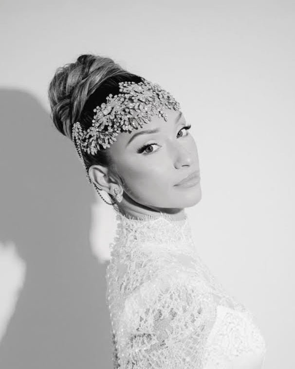 Black and white portrait of a woman wearing an ornate crystal bridal headpiece and high-necked lace dress.