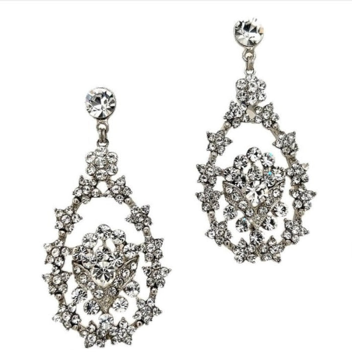 Close-up of Swarovski crystal chandelier earrings with an open teardrop design and floral-inspired detailing in silver-tone metal.
