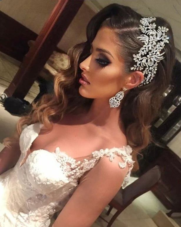 Beautiful bride looking to the side wearing a dramatic Swarovski crystal side headpiece and chandelier earrings by Bridal Styles Boutique 