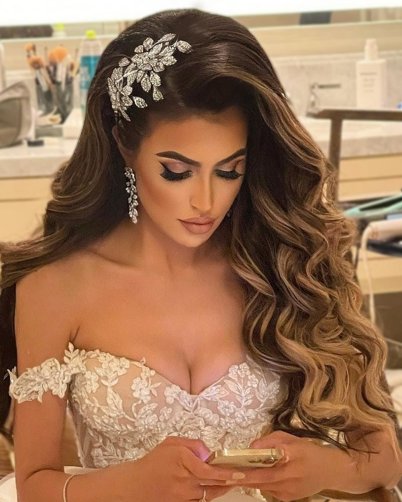 Stunning bride looking down reading her phone wearing a crystal encrusted flower bridal comb and vine bridal earrings by Bridal Styles Boutique 