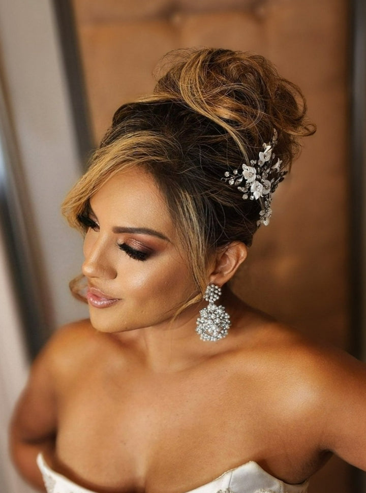 A woman in a strapless dress with glamorous makeup, elegant updo, and Studded Pearl and Crystal Chandelier Earrings (style no. E218) smiles softly as she looks down.