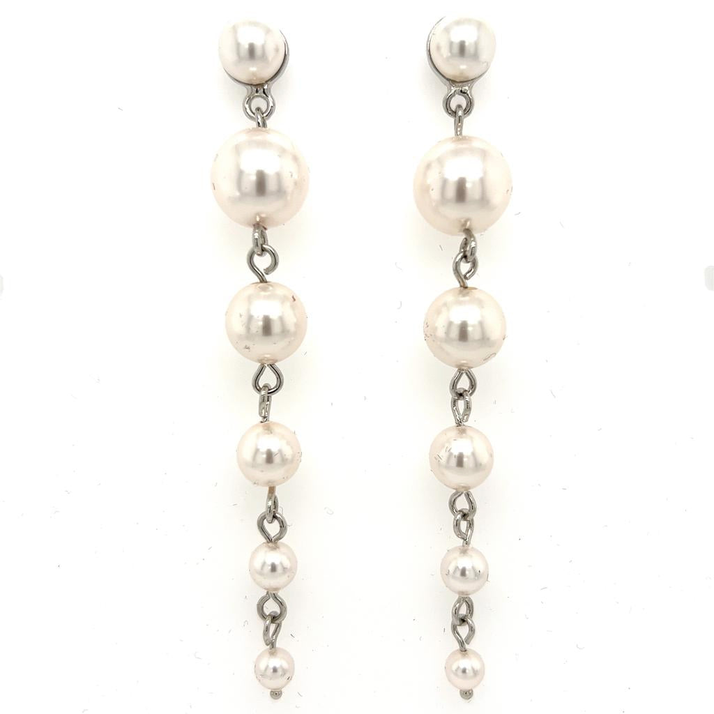 The Pearl Drop Earrings (style no. E214) feature five graduated pearls linked vertically on each silver-tone earring, with a delicate chain design. The pearls decrease in size from top to bottom for an elegant bridal look.