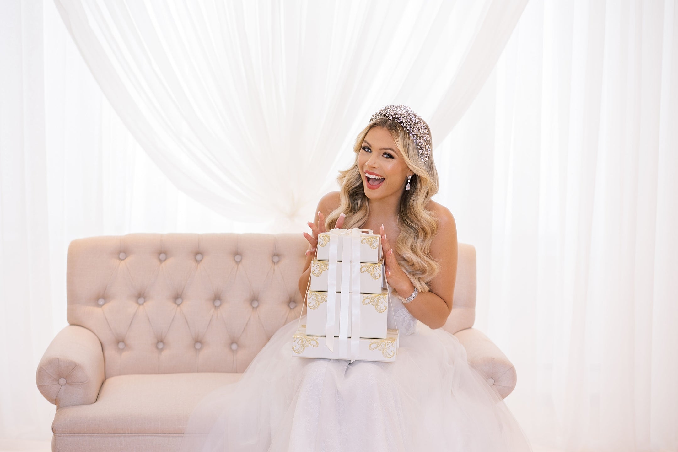 Bride wearing a crystal bridal headpiece and earrings, holding gift boxes — wedding headpieces and bridal accessories.