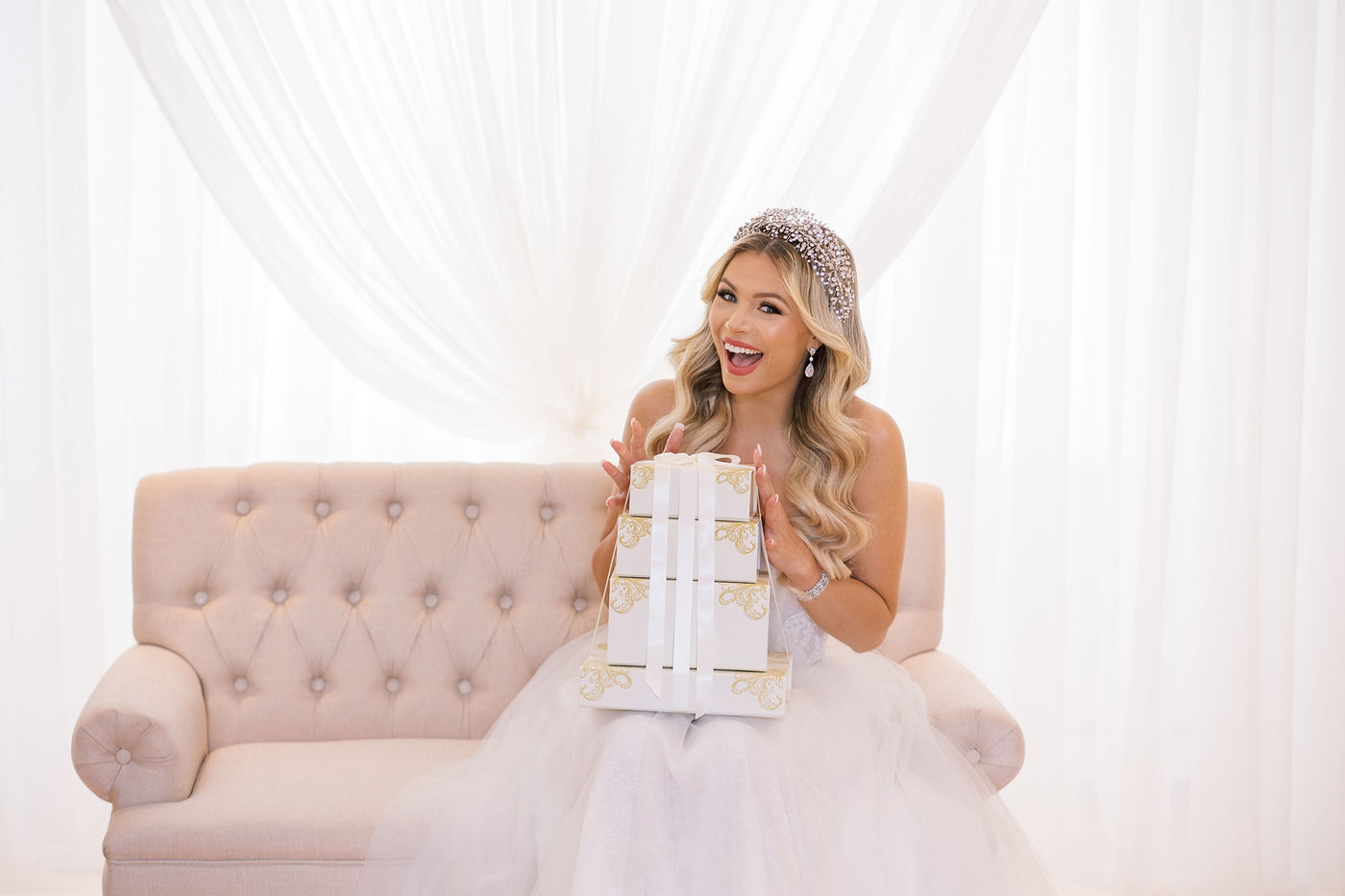 Bride wearing a crystal bridal headpiece and earrings, holding gift boxes — wedding headpieces and bridal accessories.