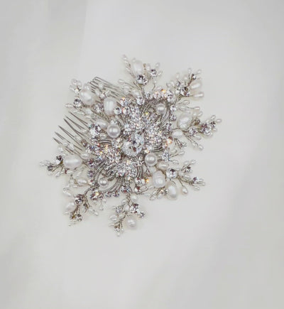 bridal hair comb with single crystal in the middle, surrounded by silver detailing and sprigs of crystal and pearl