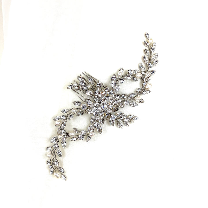 The Delicate Flowing Swarovski Hair Comb, style no. 242603, is a bridal hair accessory with a detailed branch and leaf design, embellished with clear crystals. It is shown on a soft white backdrop.