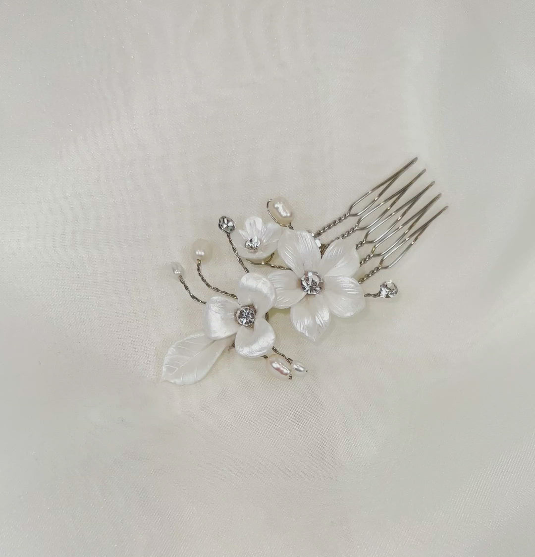 single bridal hair pin with shiny white porcelain flowers and small sprigs of crystal and pearl