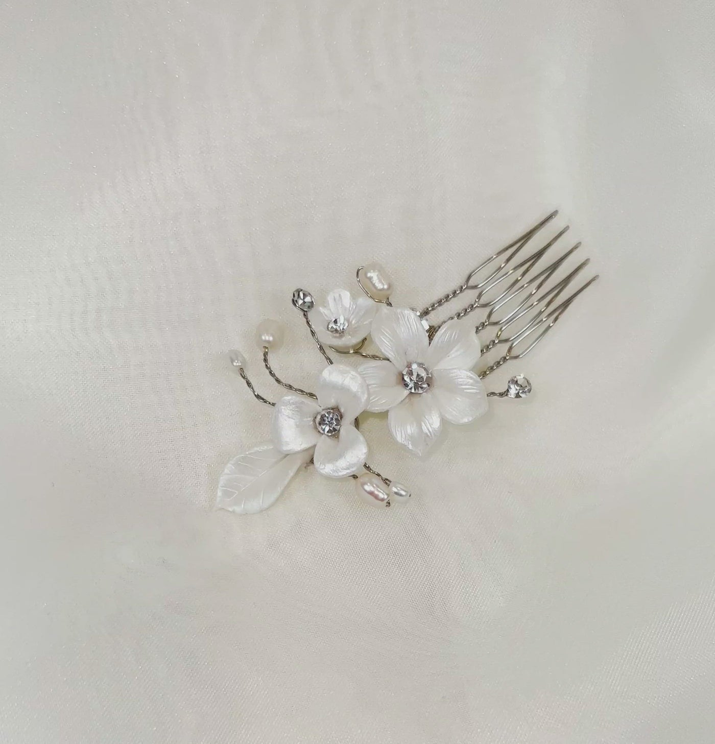 single bridal hair pin with shiny white porcelain flowers and small sprigs of crystal and pearl