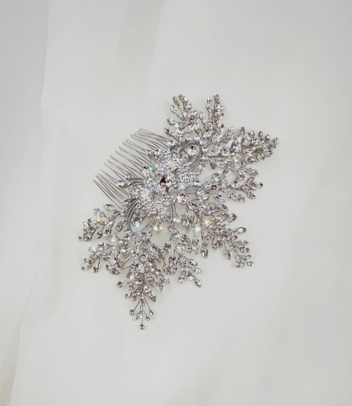 bridal hair comb with single crystal at its center surrounded by round silver detailing and sparkling sprays of crystals