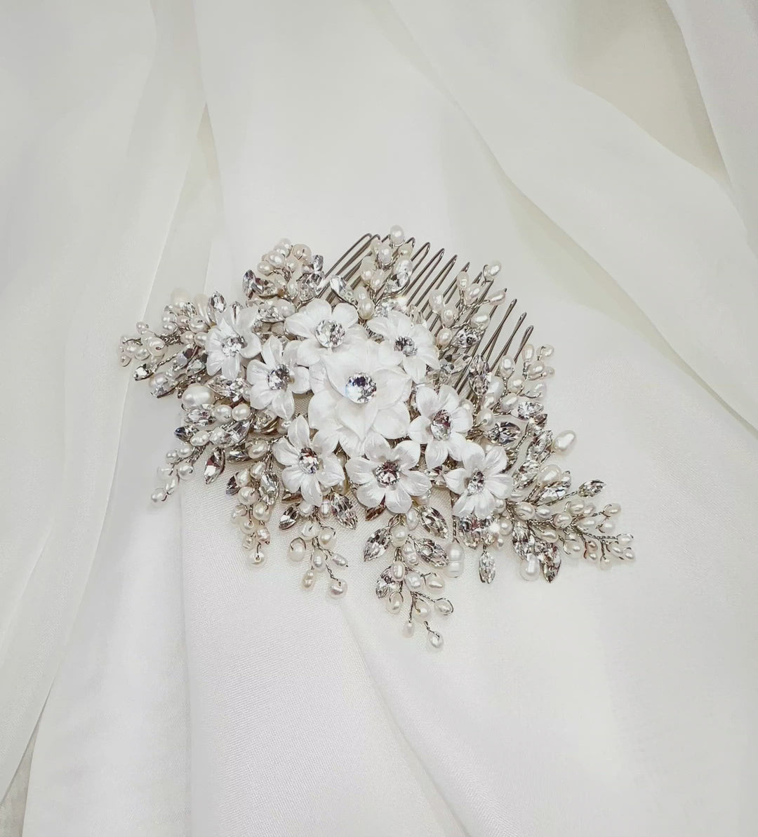 Video of a pearl and crystal bridal hair comb sparkling in the light as it is slowly rotated on soft ivory fabric