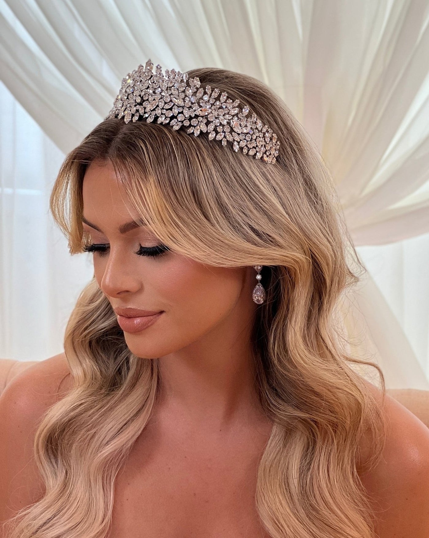 female model wearing pointed bridal crown made up of round cut crystal clusters