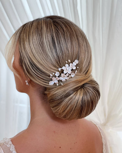 female model wearing bridal hair comb with porcelain flowers and small sprigs of crystal and pearl above an updo