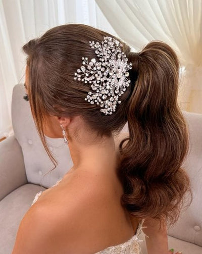 female model wearing silver bridal hair comb with single crystal center, clusters, and sparkling sprays above a ponytail