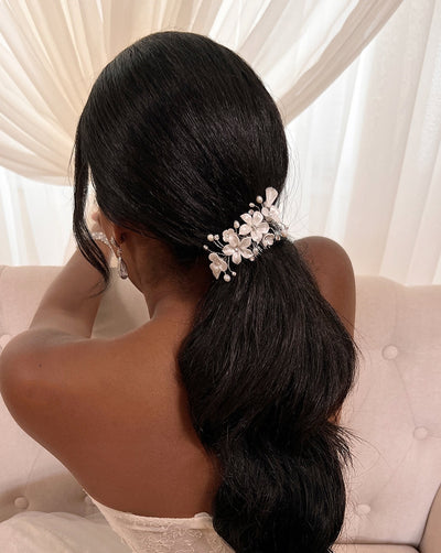 female model wearing single porcelain flower bridal hair comb with small sprigs of crystal and pearl