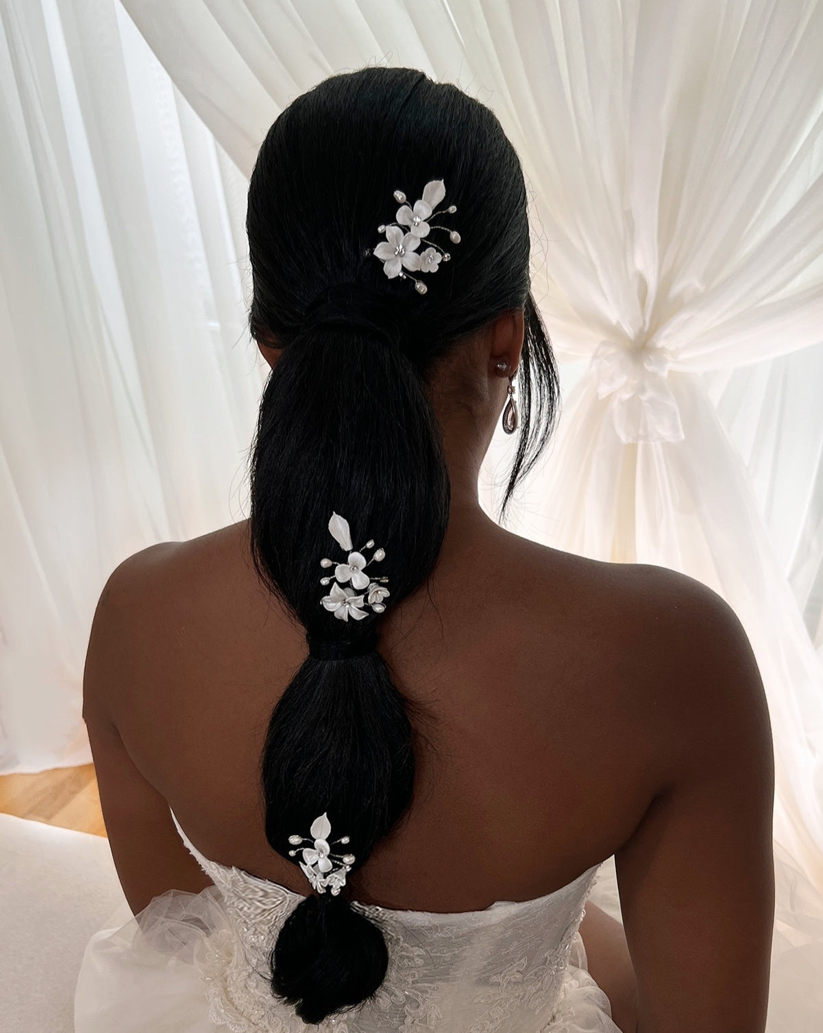 female model wearing three hair pins with porcelain flowers and small sprigs of crystal and pearl