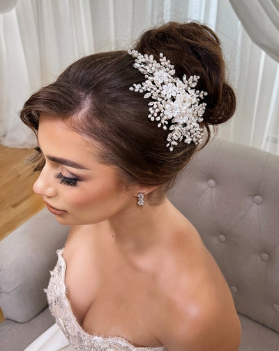 female model wearing white porcelain flower bridal hair comb surrounded by long sprays of crystal and pearl on an updo