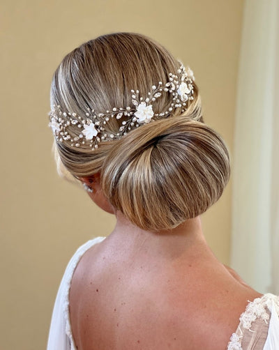 female model wearing thin looping pearl hair vine with porcelain flowers above an updo