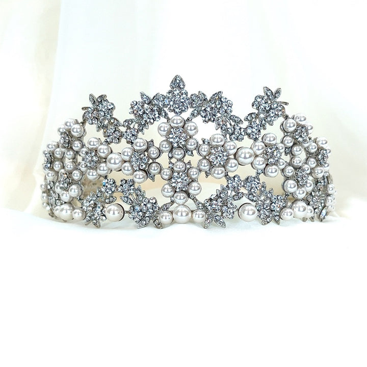 The Pearl and Swarovski Crystal Wedding Tiara, style no. 80044, is a sparkling bridal headpiece featuring intricate patterns of pearls and Swarovski crystals on a soft white base, exuding an elegant vibe.