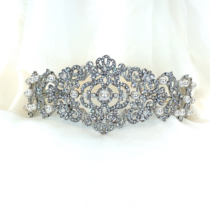 The Vintage Inspired Swarovski Crystal Headband style no. 80107 features a silver design with intricate filigree and embedded pearls, set against a white background.