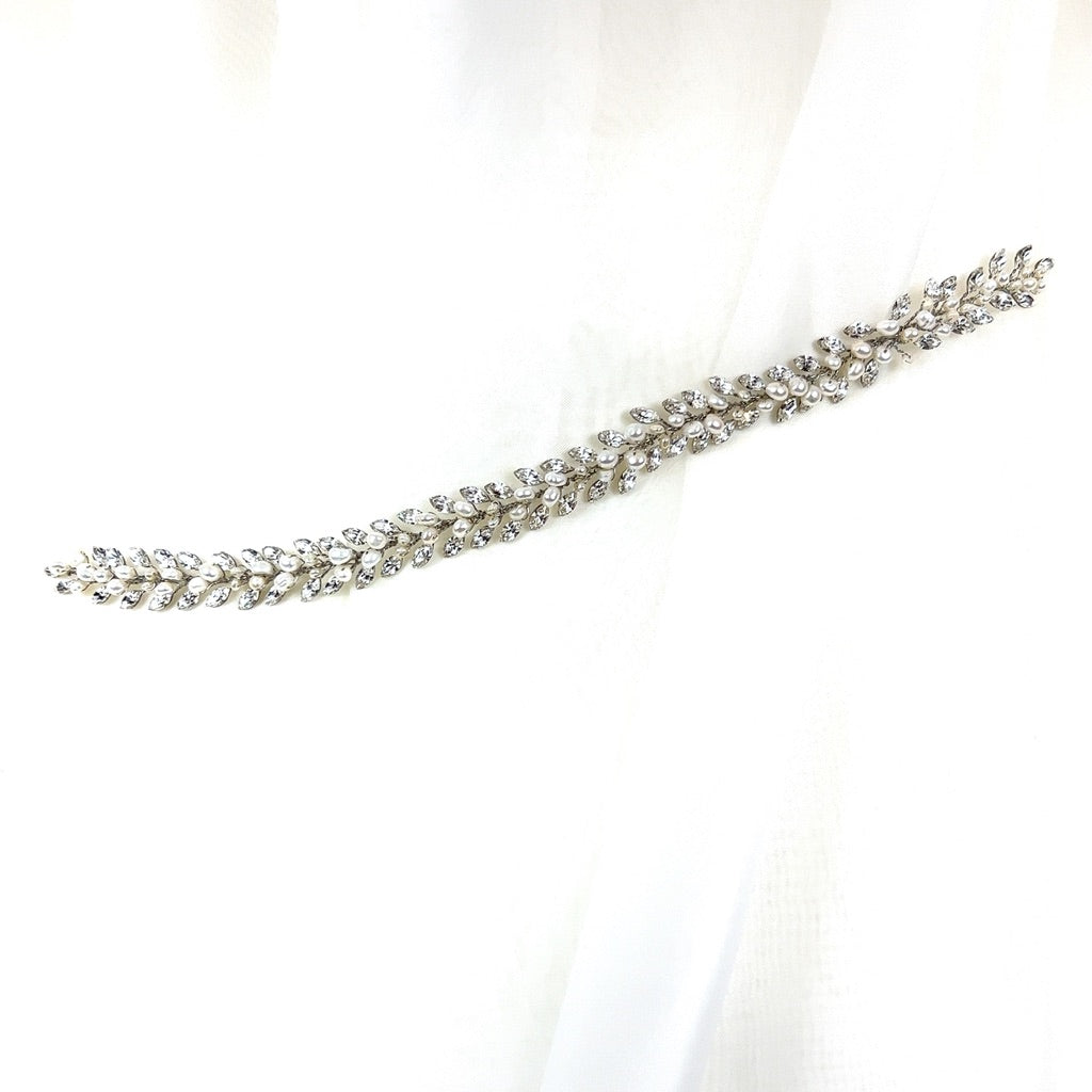 Against a soft white fabric, the Traditional Crystal Hair Vine (style no. 242710) wedding accessory, with its shimmering crystals shaped like a delicate laurel branch. 