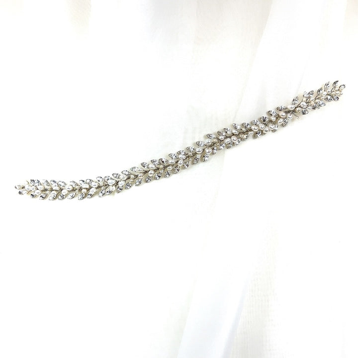 Against a soft white fabric, the Traditional Crystal Hair Vine (style no. 242710) wedding accessory, with its shimmering crystals shaped like a delicate laurel branch. 