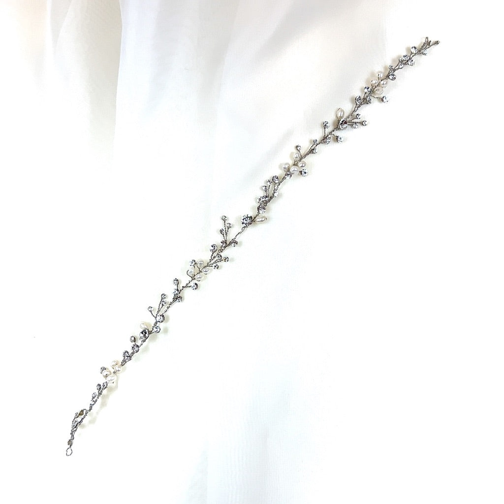 The Dainty Pearl and Crystal Vine (style no. 242700) is a delicate Swarovski crystal hair accessory with intricate vine-like design, showcasing small pearls and crystals on a white background.