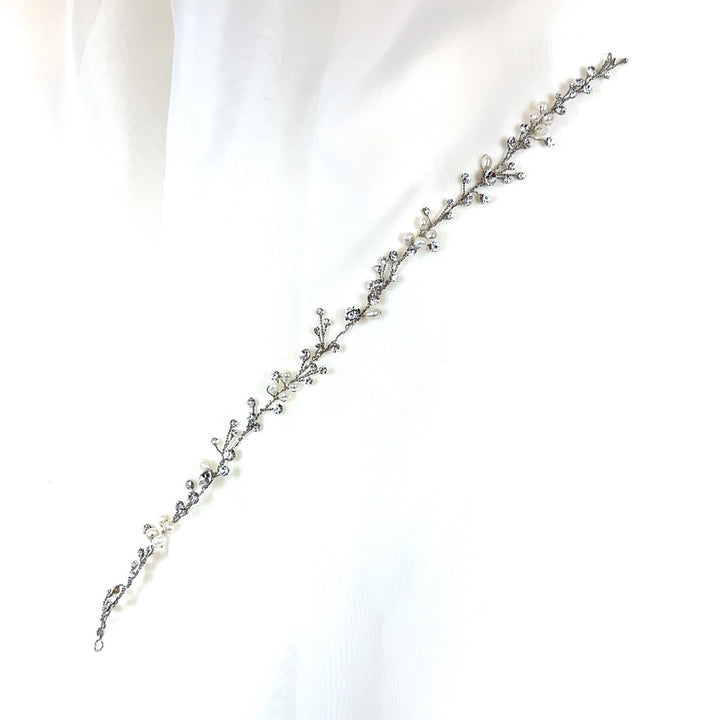 The Dainty Pearl and Crystal Vine (style no. 242700) is a delicate Swarovski crystal hair accessory with intricate vine-like design, showcasing small pearls and crystals on a white background.