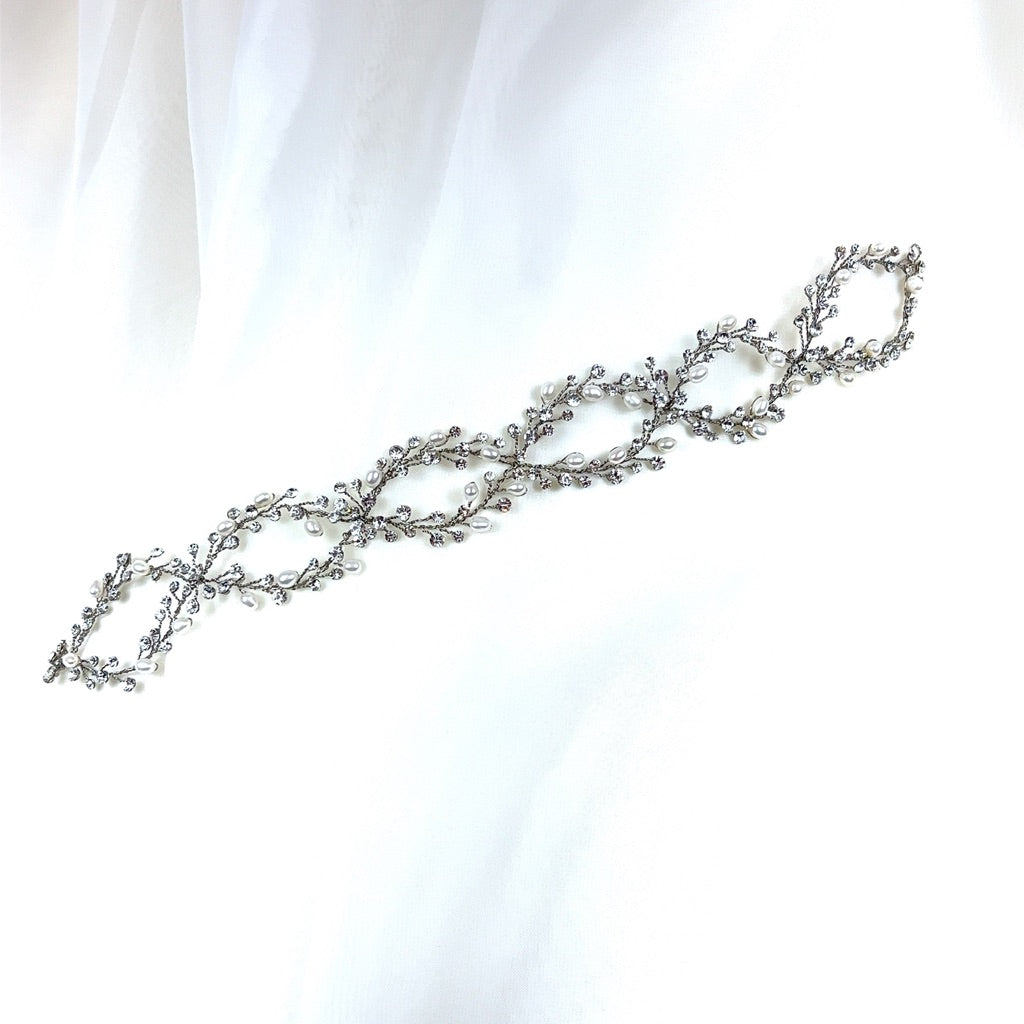 A Swarovski crystal wedding hair accessory featuring intricate leaf and branch designs with small stones.