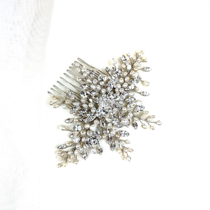 The Elegant Swarovski Crystal Bridal Comb (style no. 242512) features intricate silver branches, small white pearls, and sparkling rhinestones in a floral pattern—an ornate design.