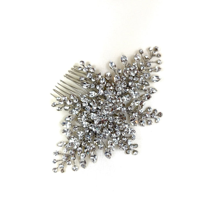 The Elegant Bridal Comb style no. 242512 features a sparkling design resembling a floral-shaped cluster of branches with round Swarovski crystals, forming a delicate snowflake. 