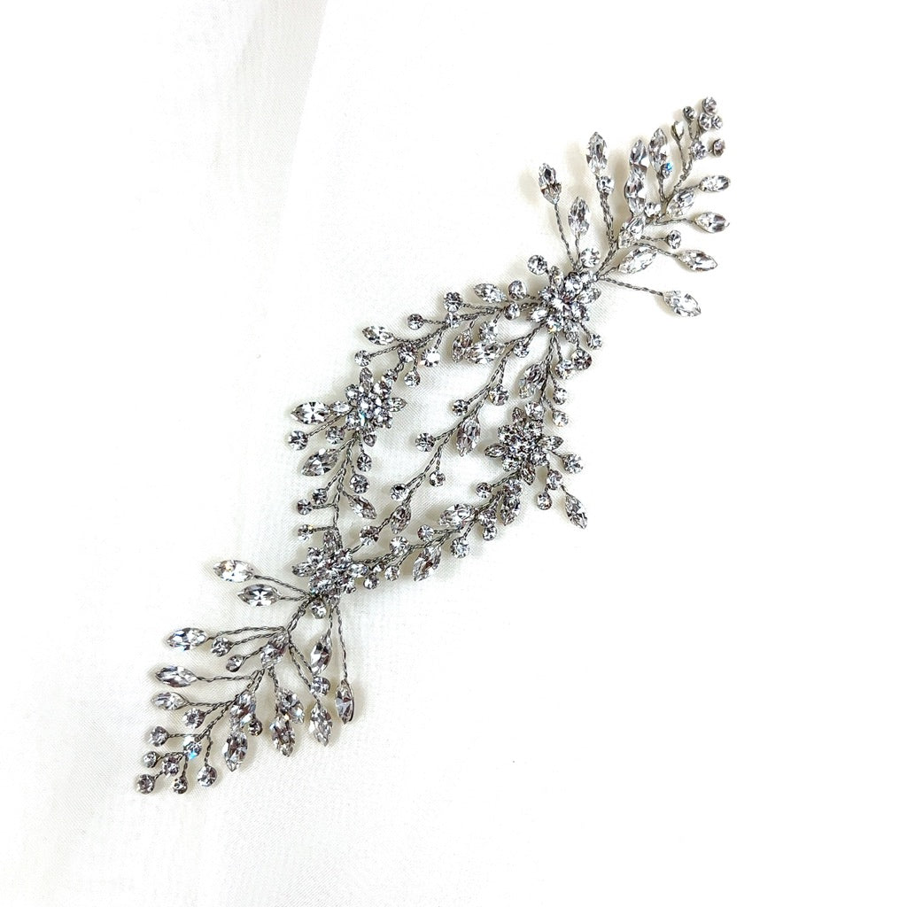 The Delicate Flowing Crystal Vine style no. 242464 is a chic Swarovski crystal hair accessory featuring an intricate motif  shaped like two leafy branches.
