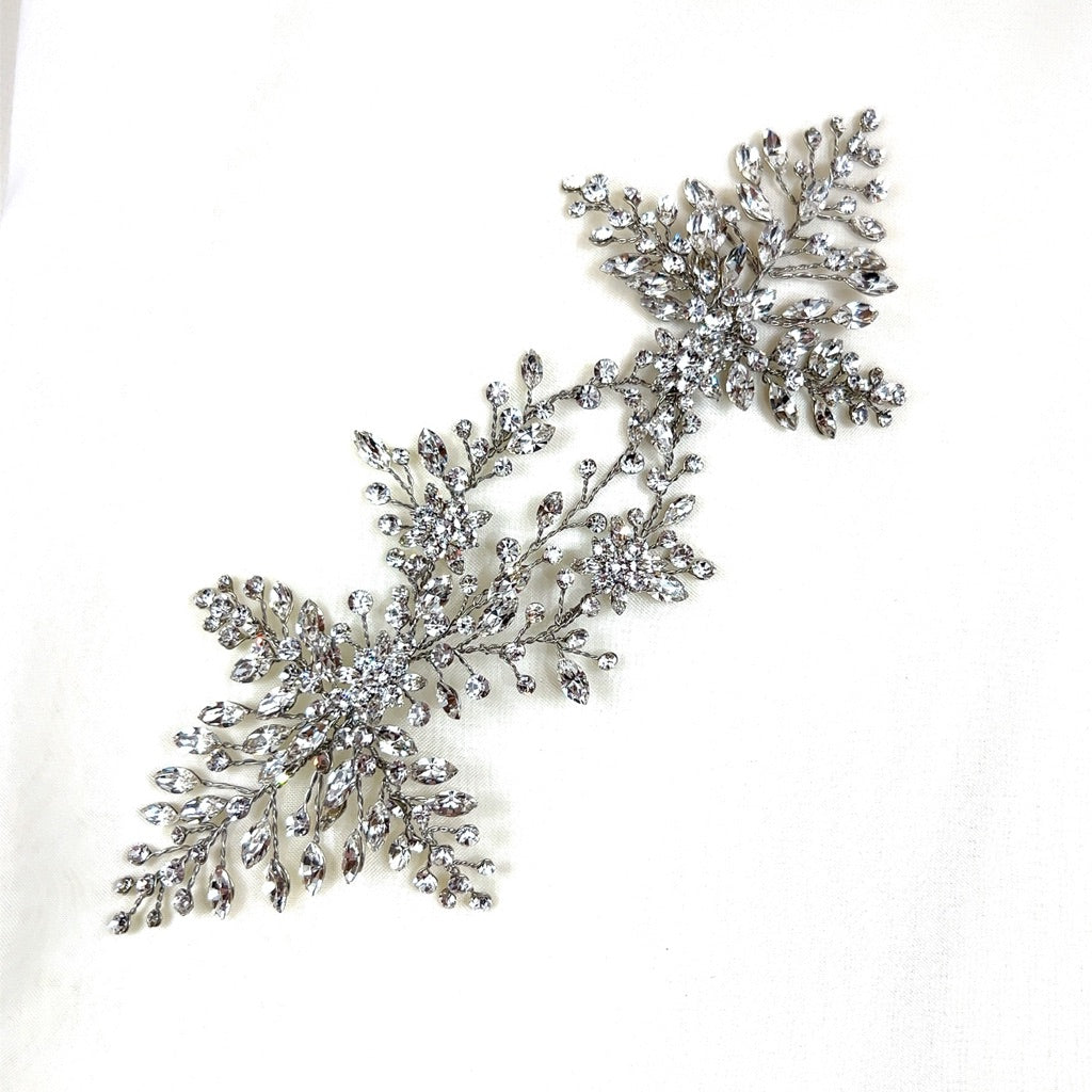 A sparkling Swarovski crystal wedding hair accessory, intricately designed with leaf and vine motifs, displayed on a white background. Product: Stunning Crystal Bridal Vine style no. 242594.