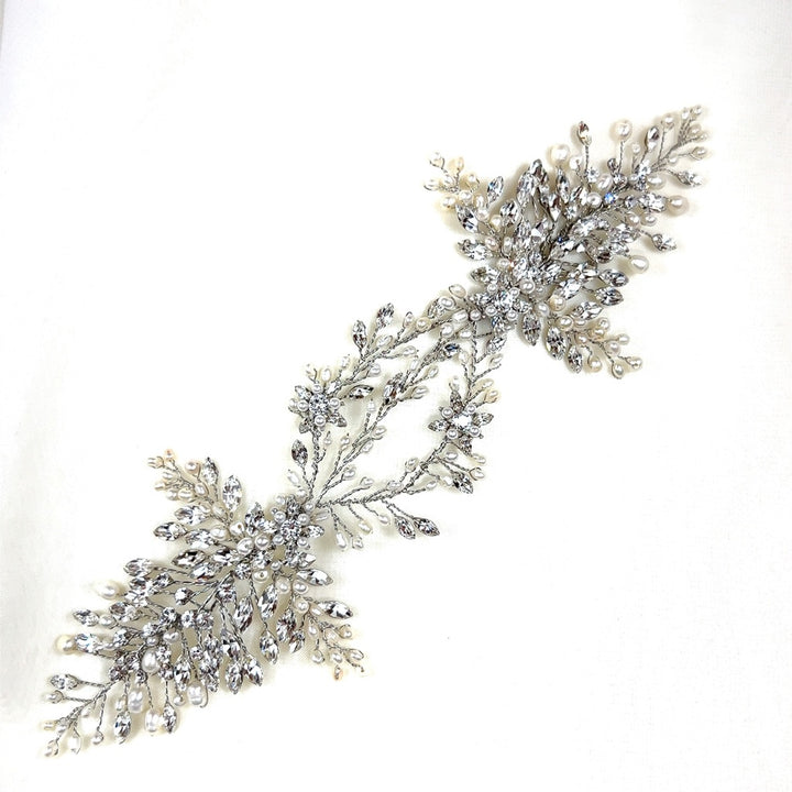 The Stunning Swarovski Crystal Bridal Hair Vine, style no. 242594, features intricate silver leaves and white pearls on a plain white background