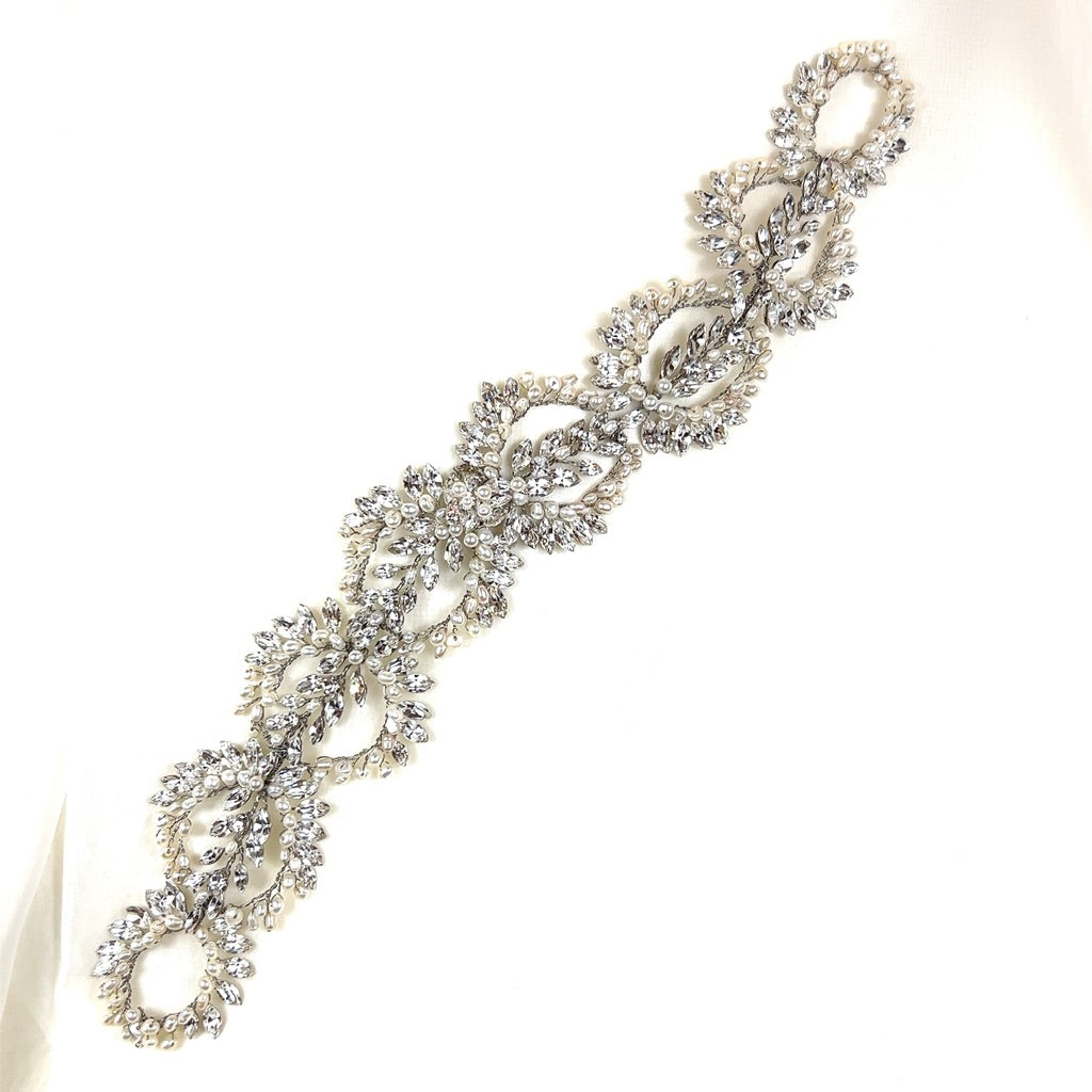 A detailed Swarovski wedding headpiece laid on a white surface.