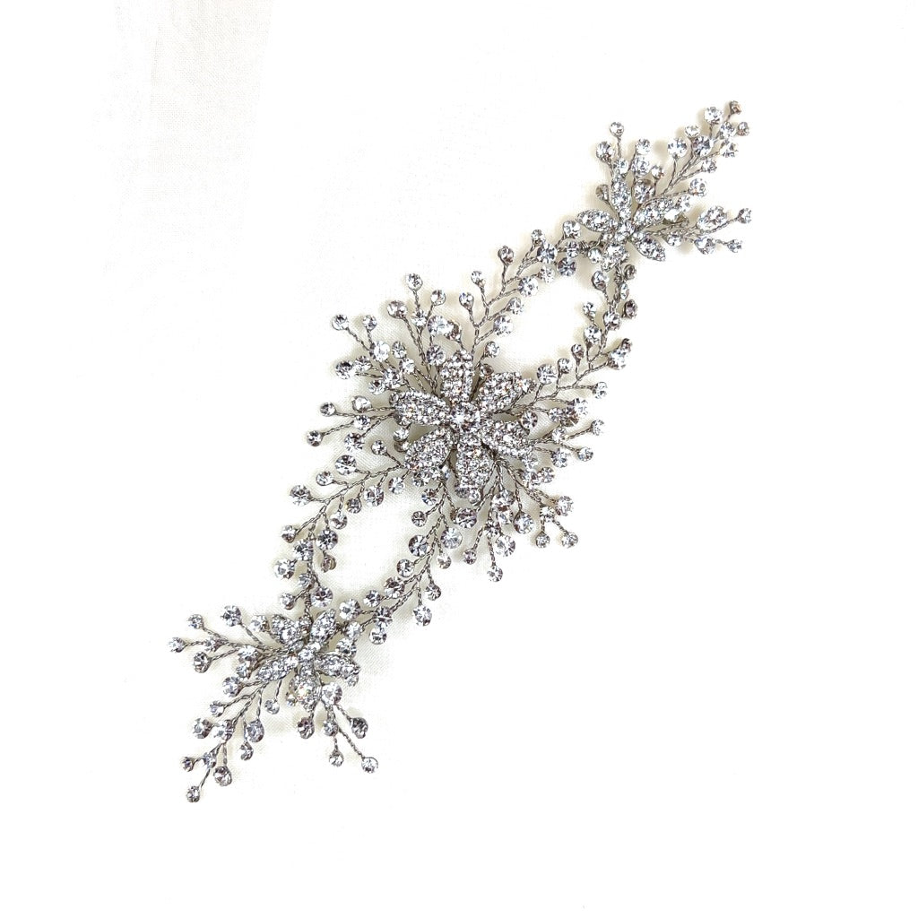 The Crystal Flower Vine (style no. 242707) is an intricate Swarovski crystal floral hair accessory with sparkling crystal embellishments forming two star-like designs, connected by delicate branches.
