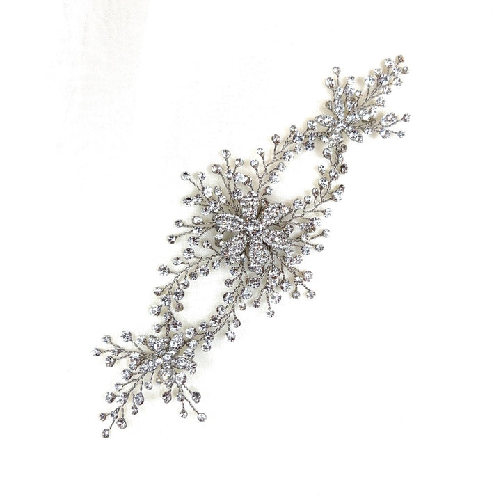 The Crystal Flower Vine (style no. 242707) is an intricate Swarovski crystal floral hair accessory with sparkling crystal embellishments forming two star-like designs, connected by delicate branches.